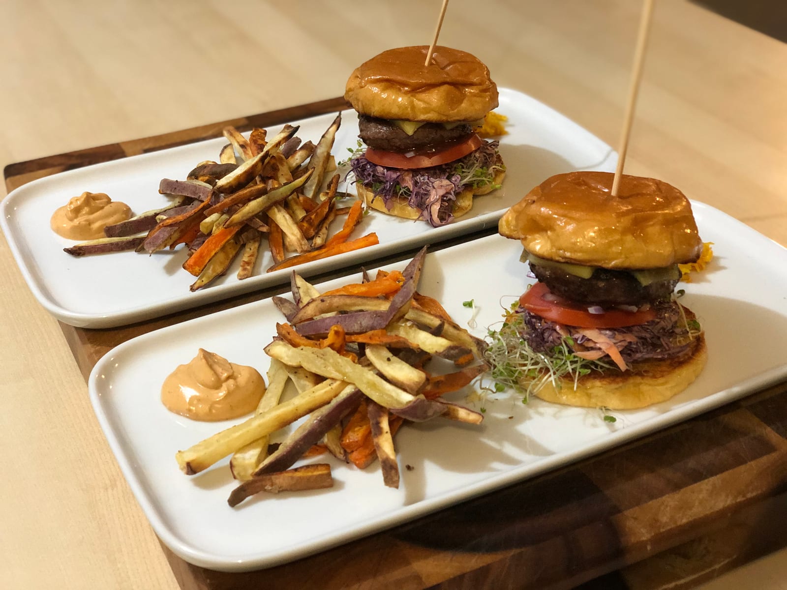 Two burgers with vegetable chips and aioli, plated for service